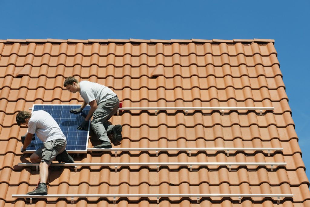 Workers installing solar panel on roof framework of new home, Netherlands